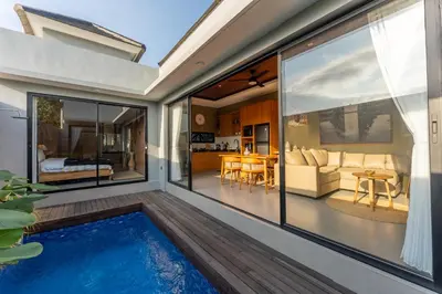 a house with a swimming pool and a living room at Villa Sattvika in Kerobokan