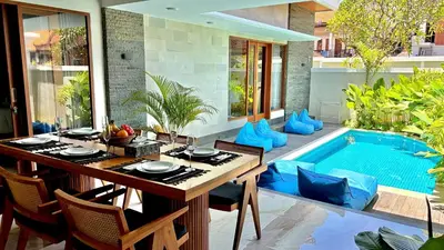 a dining table and chairs next to a swimming pool at Villa Sakura Nisa in Seminyak