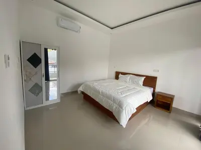 a white bedroom with a bed and a window at Hidden Homestay Jimbaran in Jimbaran