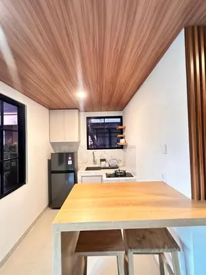 a kitchen with a wooden ceiling and a wooden table at Kubumanik Loft in Seminyak