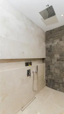 a bathroom with a shower with a stone wall at Villa By The Sea with private swimming pool in Benoa - Nusa Dua in Ujung