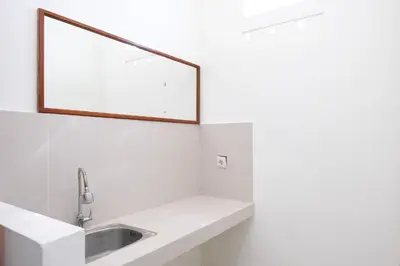 a white bathroom with a sink and a mirror at Urbanview Hotel Arta Guna Casa in Kerobokan