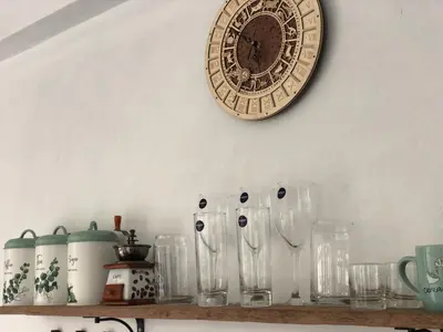a clock on a wall above a shelf with glasses at Villa Denira, Home Gym & Private Pool in Nusa Dua