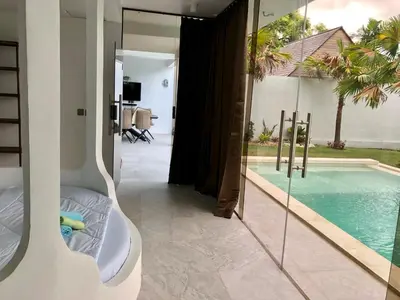 a room with a swimming pool and a bed next to a house at Villa Denira, Home Gym & Private Pool in Nusa Dua