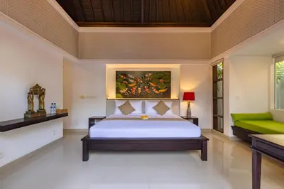 a bedroom with a bed and a green couch at Aragreen Berawa Villa in Canggu