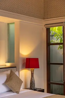 a bed with a red lamp sitting next to a window at Aragreen Berawa Villa in Canggu