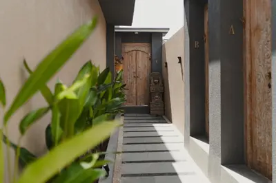 a hallway with a wooden door and some plants at Dikubu Belong VILLA in Denpasar