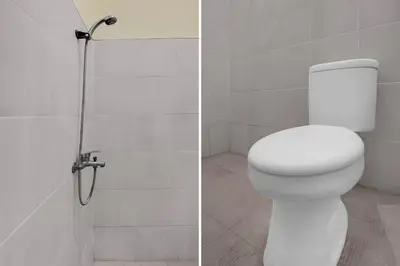 a white bathroom with a toilet and a shower at Hotel O near Trans Studio Theme Park formerly Cyloam Residence in Legian