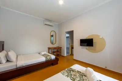 a bedroom with two beds and a tv on the wall at Cove De Pavilla in Sanur