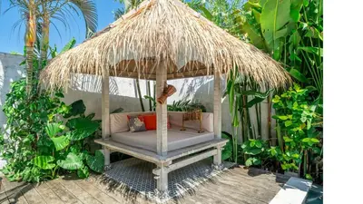 a chair under a straw umbrella in a garden at LePalms villa, 2min Beach, 10min Atlas,Finns Club in Canggu