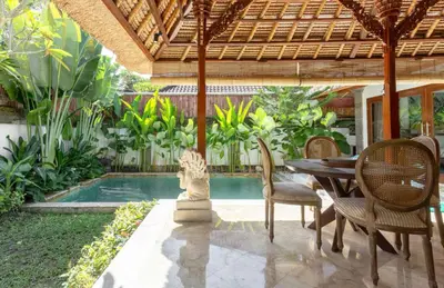 a patio with a table and chairs and a pool at Three Bedrooms Elegant Home The White Door Villa in Sanur