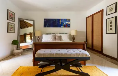 a bedroom with a bed and a large mirror at Three Bedrooms Elegant Home The White Door Villa in Sanur