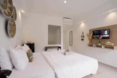 a bedroom with a white bed with a tv on the wall at Homely Bali at Rajapala in Seminyak