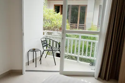 an open door to a balcony with a chair at Homely Bali at Rajapala in Seminyak