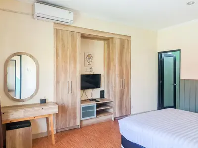 a bedroom with a bed and a mirror and a television at The Lavana Villa Singgahan Jimbaran - 3 Bedroom Villa in Nusa Dua