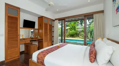 a bedroom with a bed and a tv and a pool at Villa Bidadari With Pool in Seminyak