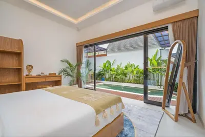a bedroom with a bed and a large window at NaraDama Villa Seminyak Bali in Seminyak