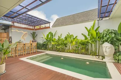 a patio with a swimming pool and a table and chairs at NaraDama Villa Seminyak Bali in Seminyak