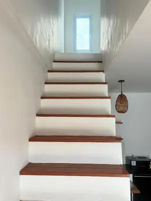 a staircase in a house with white walls and wooden floors at Home Stay Room in Bali Near Sanur Beach in Sanur