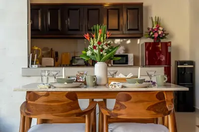 a kitchen table with a vase of flowers on it at Arts Heliconia Villa Two-Bedroom Private Pool Kuta in Kerobokan