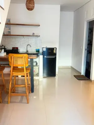 a kitchen with a table and chairs and a black refrigerator at Home Stay Room in Bali Near Sanur Beach in Sanur