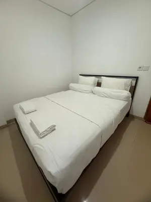 a bed with white sheets and a book on it at Home Stay Room in Bali Near Sanur Beach in Sanur