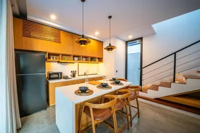 a kitchen with a table and chairs and a refrigerator at Divija Villa by Unicorn Villas Bali in Kerobokan