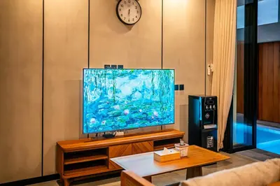 a living room with a large television and a clock at Divija Villa by Unicorn Villas Bali in Kerobokan