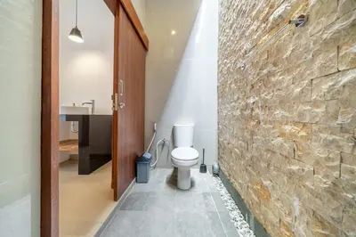 a bathroom with a toilet and a stone wall at 3BR Pool Villa in Berawa - Walk to Beach & Cafes in Canggu