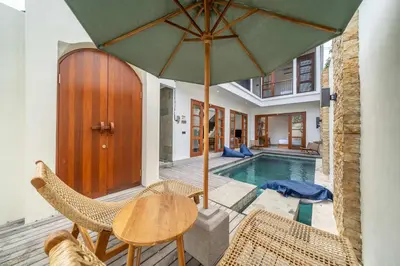 a patio with a table and chairs and a pool at 3BR Pool Villa in Berawa - Walk to Beach & Cafes in Canggu