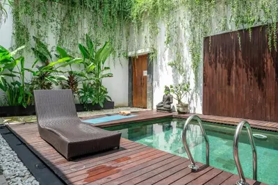 a swimming pool with a chair on a wooden deck at Modern Tropical 2BR Villa in Seminyak Kuta with Pool & Garden in Legian