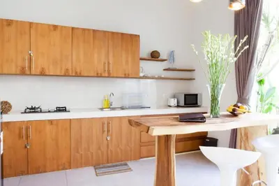 a kitchen with wooden cabinets and a wooden table at Modern Tropical 2BR Villa in Seminyak Kuta with Pool & Garden in Legian