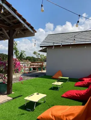 a backyard with green grass and red pillows and a building at RBE Hotel Kuta 2- 5 Min to Airport&Beach by Micky Studio in Ngurah Rai International Airport