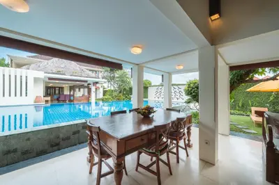 a dining room with a table and a swimming pool at The Cemara Umalas in Kerobokan