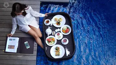 a woman sitting on a table with plates of food at Abia Villa Legian in Legian