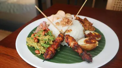 a plate of food with meat and rice on a table at Abia Villa Legian in Legian