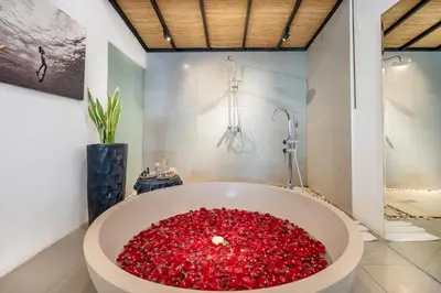 a bathroom with a large tub filled with red flowers at Semesta Collection Seminyak Villas in Seminyak