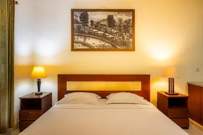 a bedroom with a large bed with two nightstands and two lamps at TheNadram Guest House in Kerobokan