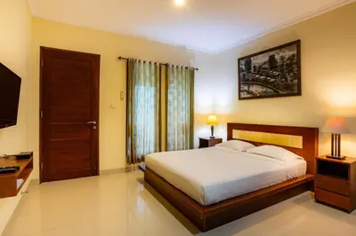 a bedroom with a bed and a flat screen tv at TheNadram Guest House in Kerobokan