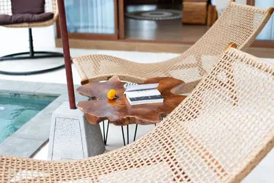 a wooden coffee table sitting on a chair next to a pool at Villa O'Anne 3 in Seminyak