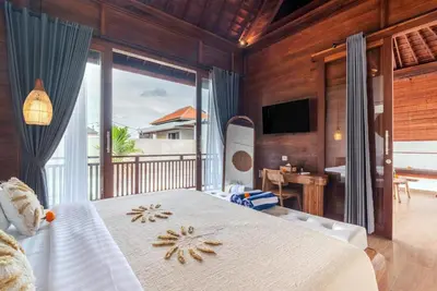 a bedroom with a bed and a balcony with a television at Villa O'Anne 3 in Seminyak