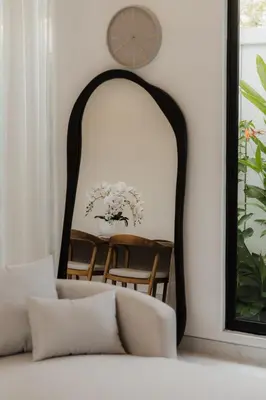 a mirror behind a couch with a clock on the wall at Villa Toku by BaliSuperHost in Seminyak