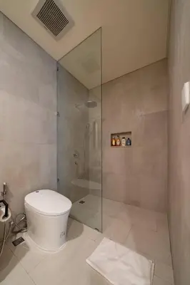 a bathroom with a toilet and a glass shower at Kona Resort - Seminyak in Kerobokan
