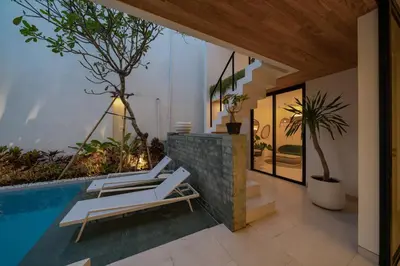 a villa with a pool and two lounge chairs at Kona Resort - Seminyak in Kerobokan