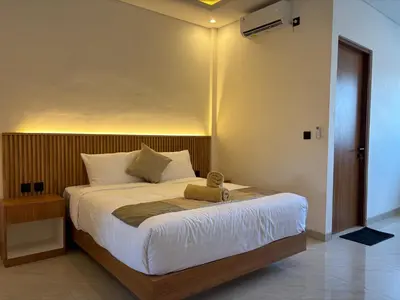 a bedroom with a large bed with white sheets at Taman Sari Guesthouse in Kerobokan