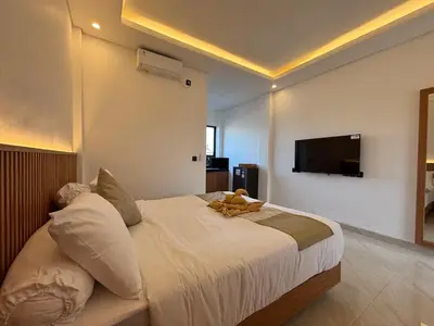 a bedroom with a bed with a television on the wall at Taman Sari Guesthouse in Kerobokan