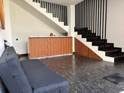 a couch sitting in a room with a staircase at Taman Sari Guesthouse in Kerobokan