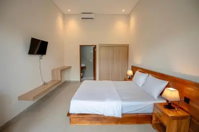a bedroom with a white bed and a television at Abimanyu Guest House in Seminyak