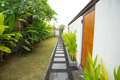 a garden with a walkway next to a building at Abimanyu Guest House in Seminyak