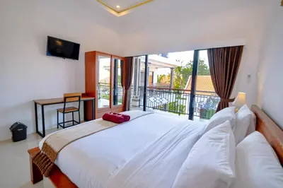 a bedroom with a large white bed and a balcony at Crystal Flow Guest House & Apartment Canggu in Canggu